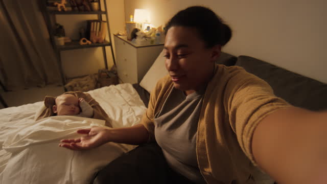 Happy Mom Making Selfie Video for Blog with Sleeping Baby