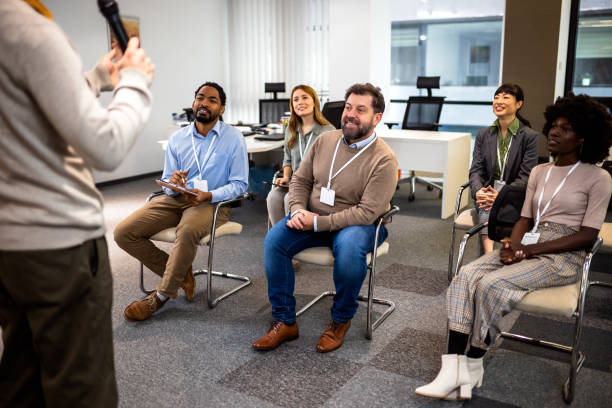istock Young business man lecturing his multiethnic colleagues. Having a speech while holding a microphone. 2046252438