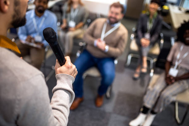 istock Young business man lecturing his multiethnic colleagues. Having a speech while holding a microphone. 2046252442