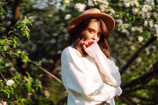 istock Young woman stands near a blossoming tree in a spring park. 2046256678