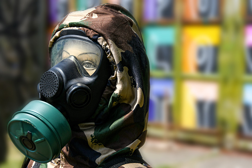 Mannequin head with gas mask and camouflage military hood with colorful background