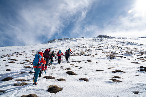 Alpinist climber team is on expedition  on the mountain,  they are walking in a row in the video while drone is recording them.