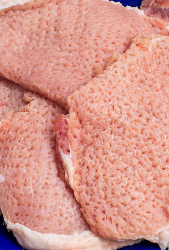 Background of closeup tenderized pork. The tenderloins are hammered or heavy pounded to make it flatter or thinner. Easier to cook. Good concept for meat preps or designing ideas for food sale.