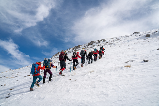 Alpinist climber team is on expedition  on the mountain,  they are walking in a row in the video while drone is recording them.