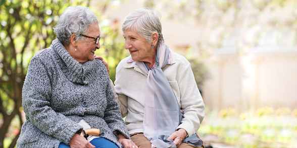 Happy mature women communicating with their husbands while relaxing in spring day on a terrace. Men are in the foreground.