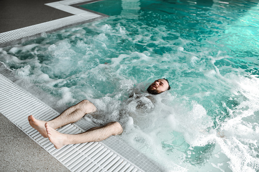 Male Finding Balance With Upper Body Floating In Pool Water And Grounded Feet