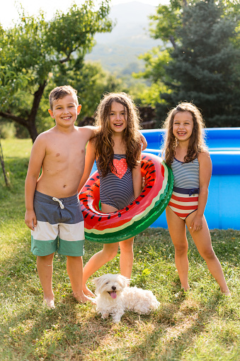 Children having fun swimming in inflatable pool and enjoys summer vacation in the yard