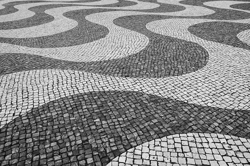 Typical Portuguese mosaic cobble stone paving in Lisbon, Portugal, black and white.
