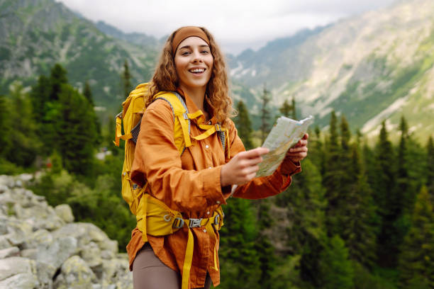 istock Stylish woman with backpack hiking, and map 2046345772
