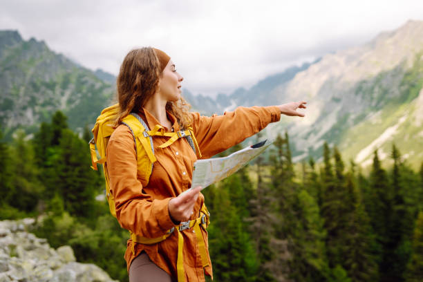 istock Stylish woman with backpack hiking, and map 2046345773