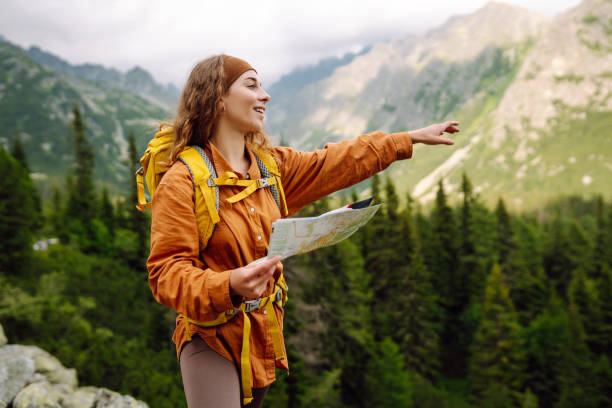 istock Stylish woman with backpack hiking, and map 2046345777