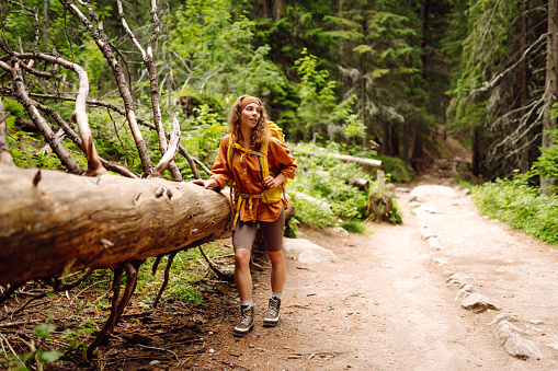 Beautiful traveling woman  in the mountains on a background of a forest. Hiking, active lifestyle. Outdoor recreation concept.