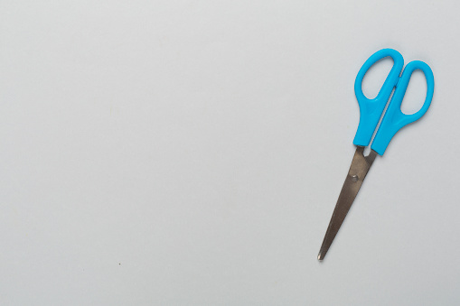 Blue scissors on color backgroung, top view