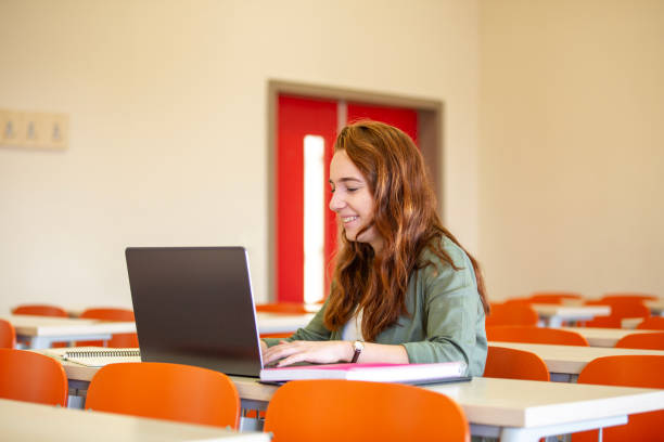 istock Happy female student using laptop in the classroom alone 2046380542