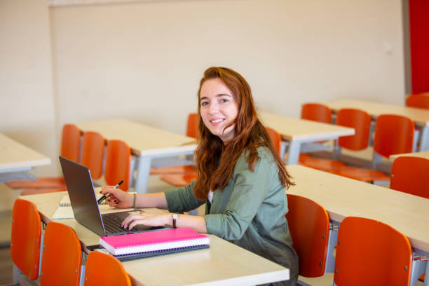 istock Happy female student using laptop in the classroom alone 2046381585
