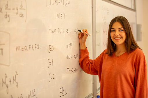 Young and beautiful student studying mathematical formula in front of whiteboard