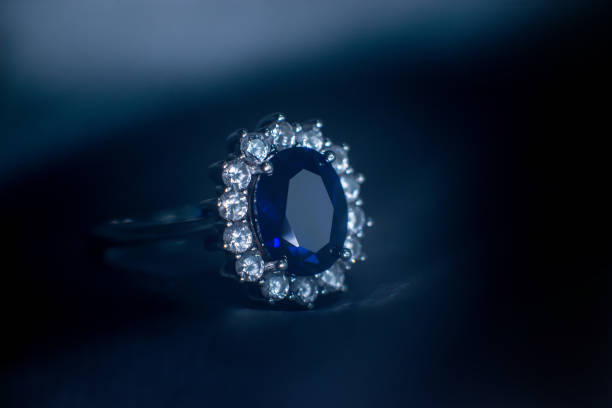 Green emerald fashion engagement diamond ring on green satin background. Luxury female jewellery, close-up. Selective focus