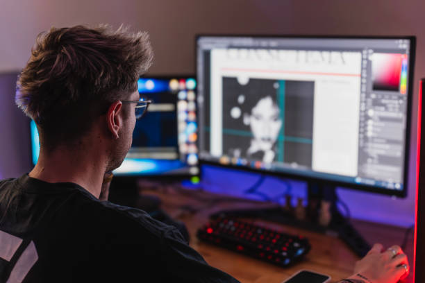 Young graphic designer working with two screens in his bedroom