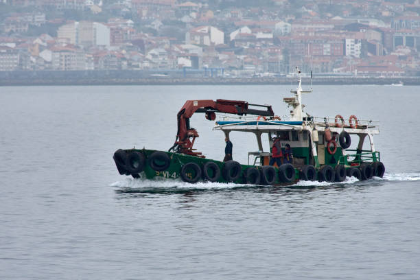 Vigo, Pontevedra, Spain; March, 03, 2021; A green mussel boat returns and heads to the punts with the workers ready on board.