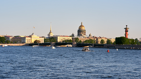 Cityscape of old history buildings on embankment Neva river, Saint Isaac's Cathedral and Spit of Vasilievsky Island, Saint-Petersburg, Russia. Blue clear sky.