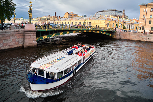 Saint Petersburg. Russia - June 08, 2023: Cityscape of the water Fontanka river with recreational boat and embankment with old residential multicolor buildings in the historical center of St. Petersburg, Russia. Belinsky Bridge
