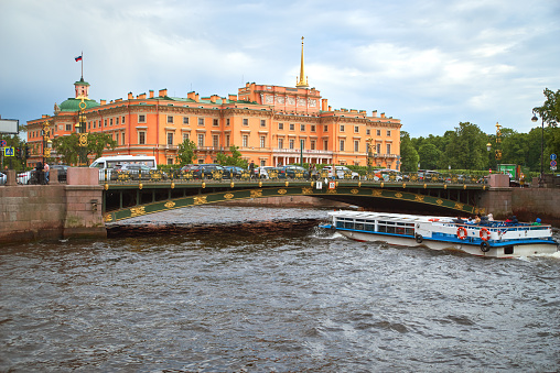 St. Petersburg, Russia - June 08, 2023: Saint Michael's castle (Mikhailovsky Castle or Engineers' Castle). Cityscape of the water Fontanka river with recreational boat and Belinsky bridge.