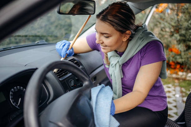 istock Young woman cleaning dust using brush inside of her car 2046493331