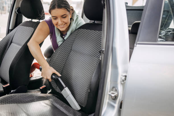 istock Young woman cleaning drivers seat using vacuum cleaner 2046495438