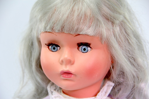 Close up of an old doll on a white background. Creepy old doll. Retro style antique doll.