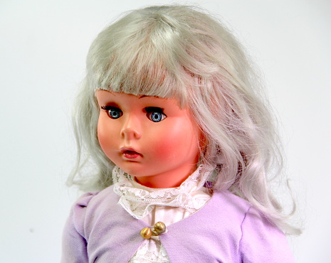 Close up of an old doll on a white background. Creepy old doll. Retro style antique doll.