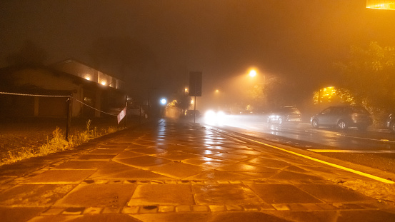 Pedestrian walkway and car moving through the city on misty winter night.