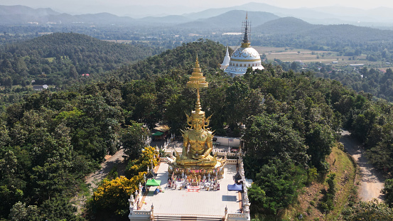 Top view of Phra Maha Jakkaphat in Thai Buddhist art is a large golden Buddha statue sitting outdoors on a hill. Inside Wat Phra That Doi Saket. This temple is another important temple in Northern Thailand.