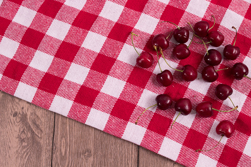 Picnic tablecloth with red and white checkered cherries on wooden table