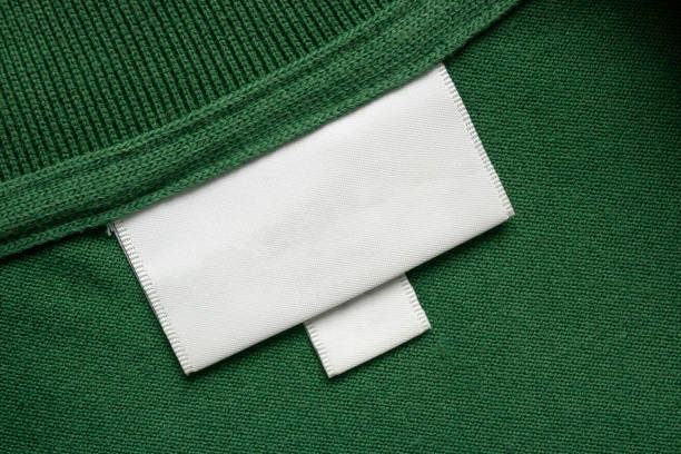Blank white laundry care clothes label on green shirt fabric texture background
