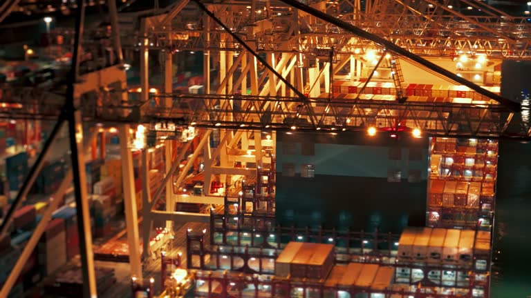 AERIAL Drone Shot of Cargo Ship Moored at Illuminated Industrial Port in City at Night