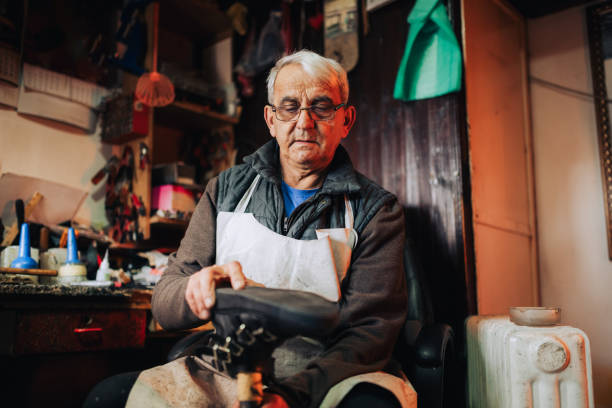 istock A senior cobbler is fixing an old boot in his workshop. 2046629785