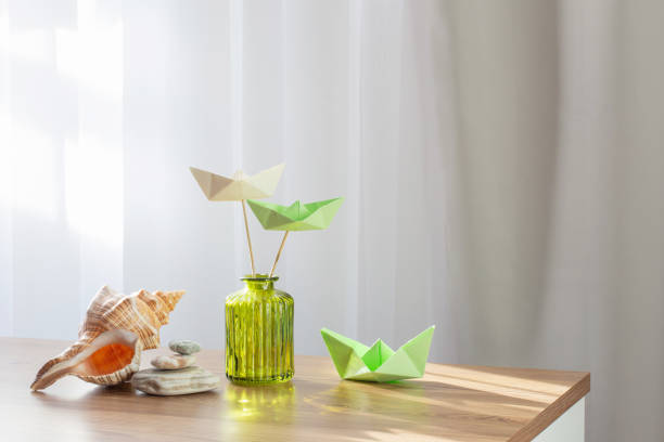 paper boats in green glass vase on wooden table - nautical vessel isolated toy boat wood photos et images de collection