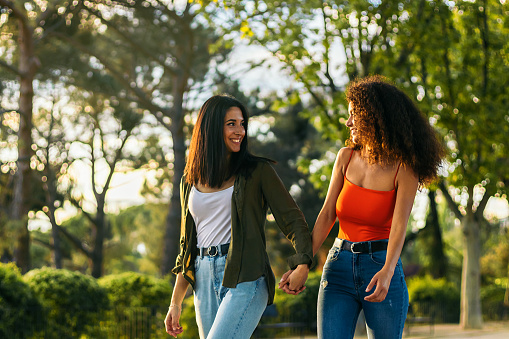 two young women couple walking holding her hands in a park