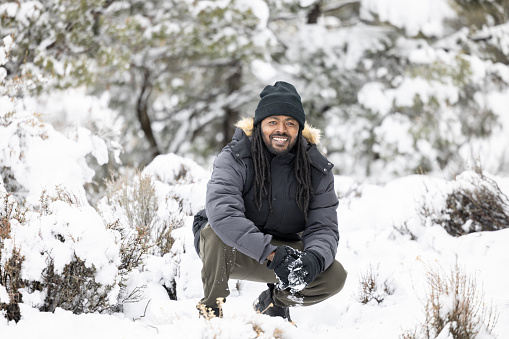 Man in fur winter hat with ear flaps smiling poextreme in the forest