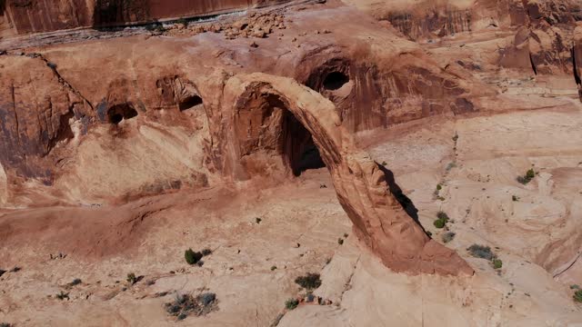 A high-flying drone shot of the Corona Arch, a massive natural sandstone arch located in a side canyon of the Colorado River, just west of Moab, Utah.