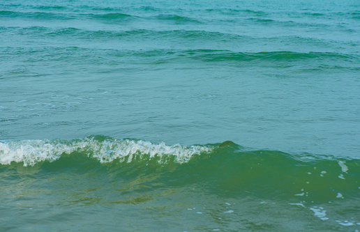 Waves on the beach. Blue sea wave. Blue water surface texture with ripples, splashes, and bubbles. Abstract summer banner background Water waves in sunlight with copy space cosmetic moisturizer.