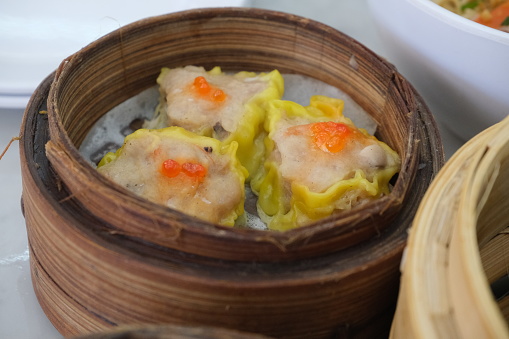 Traditional Asian dish called shu mai, dim sum dumplings in bamboo steamer, close up view.