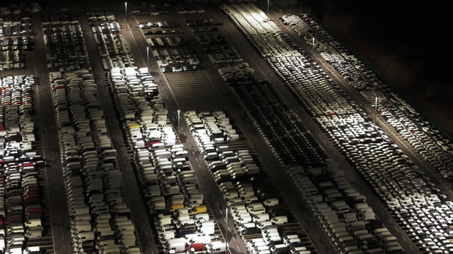 AERIAL Drone Shot of Auto Terminal Parking Lot Full of New Motor Vehicles at Night