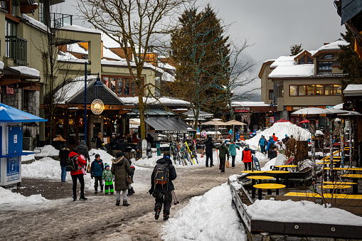 Whistler, B.C., Canada - Feb. 29, 2024: Photo of people walking on the Village Stroll commercial section at Whistler Village after a day of snow and rain.