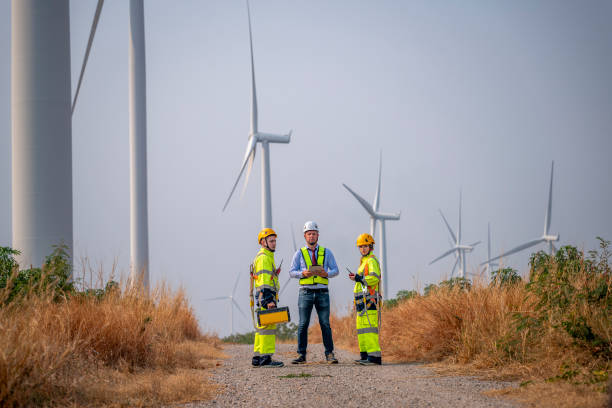 istock Engineer wearing uniform ,helmet hold document inspection work in wind turbine farms rotation to generate electricity energy. Green ecological power energy generation wind sustainable energy concept. 2046932922