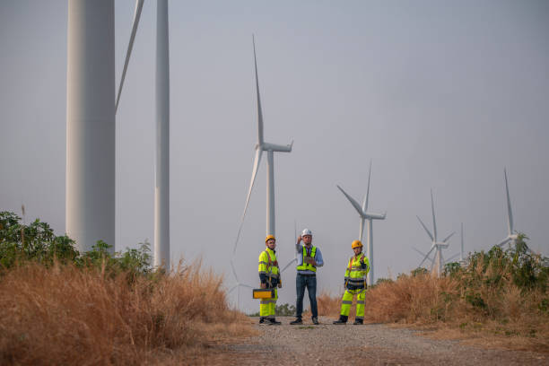 istock Engineer wearing uniform ,helmet hold document inspection work in wind turbine farms rotation to generate electricity energy. Green ecological power energy generation wind sustainable energy concept. 2046932923