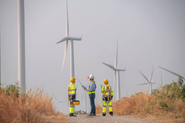 istock Engineer wearing uniform ,helmet hold document inspection work in wind turbine farms rotation to generate electricity energy. Green ecological power energy generation wind sustainable energy concept. 2046933479