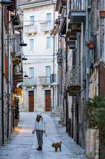 Scanno, Italy Feb 15, 2024 A young woman with a dog walks in the narrow alley of this historic village.