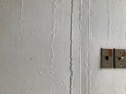 two antique light switches mounted on a rough white-painted cement wall, using for background