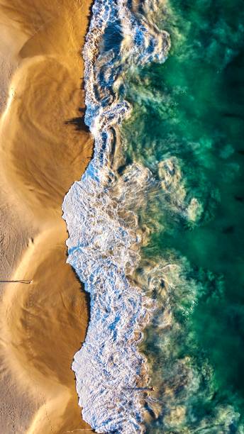 istock Waves Crashing upon a golden sand beach. 2046946935